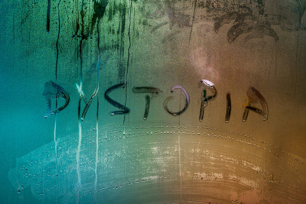 le mot dystopie écrit à la main sur la surface en verre de fenêtre humide - Photo, image