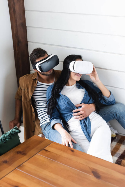 young man hugging girlfriend smiling while gaming in vr headset - Foto, immagini