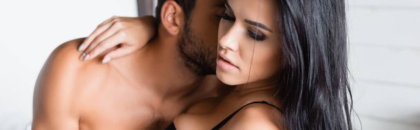 χωρίς πουκάμισο άντρας φιλάει σέξι μελαχρινή γυναίκα αγκαλιάζει το λαιμό του, λάβαρο - Φωτογραφία, εικόνα