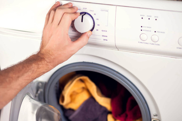 Männerhand schaltet Waschmaschine ein und wählt Waschmodus - Foto, Bild
