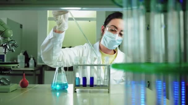 Вчений в лабораторії проводить хімічний експеримент з синьою рідиною в пробірках
 - Кадри, відео