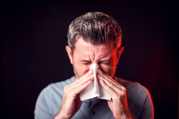 Man has a runny nose and snot in napkin. People, healthcare and medicine concept - Photo, Image