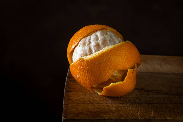 Orange on a wooden surface. Citrus fruit. Peeled orange wrapped in orange peel - Foto, Bild