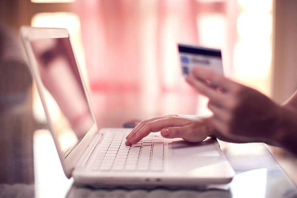 Woman holds credit card and does online payment with laptop. Online shopping and technology concept - Foto, Imagen