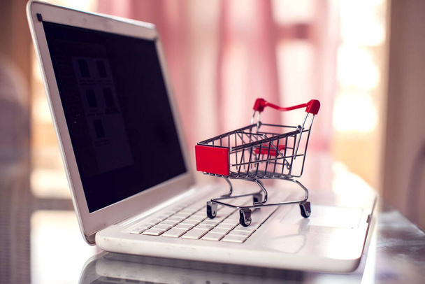 買い物用のトロリーはラップトップに残っています。オンラインショッピングとビジネスコンセプト - 写真・画像