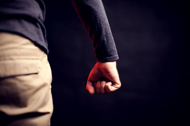 L'homme montre son poing devant un fond noir. Personnes, violence familiale, concept de criminalité - Photo, image