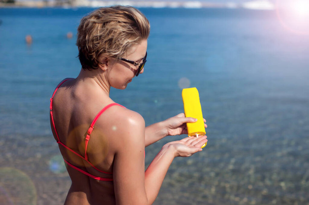 Female applies sun protection cream on her skin. People, healthcare and summer concept - Photo, Image