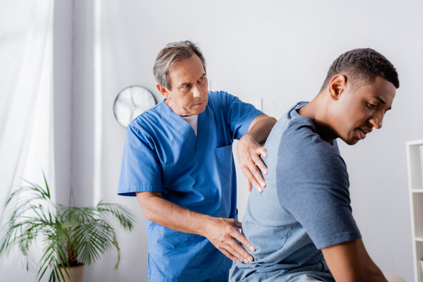 mature chiropractor working with young african american man  - Photo, Image