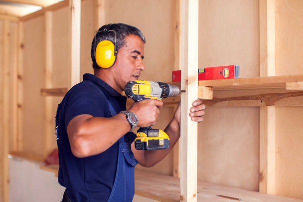Handyman avec écouteurs jaunes fonctionne avec perceuse ne répare. - Photo, image