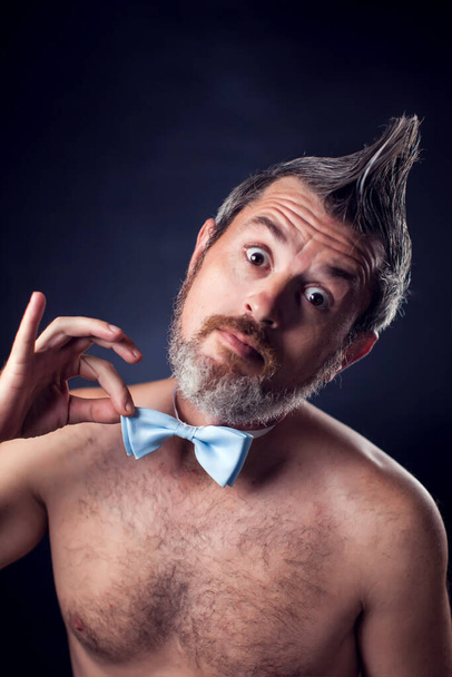 Portrét legračního nahého muže s ironií nošení motýlí kravaty před černým pozadím  - Fotografie, Obrázek