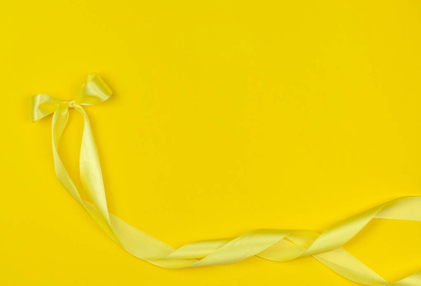 Cinta de satén amarillo sobre fondo amarillo.Trending Colors 2021 - Foto, imagen