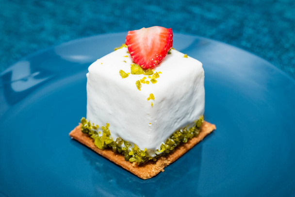 curd cake with a slice of fresh strawberry on a blue background. The cake is on a blue plate. Close-up - Fotoğraf, Görsel