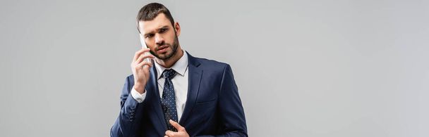 серйозний бізнесмен розмовляє на смартфоні ізольовано на сірому, банер
 - Фото, зображення