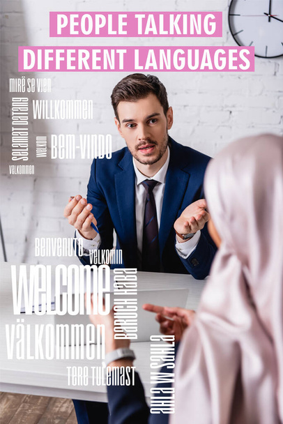 translator pointing with hand while talking to arabian businesswoman on blurred foreground, welcome word in different languages illustration - Photo, Image
