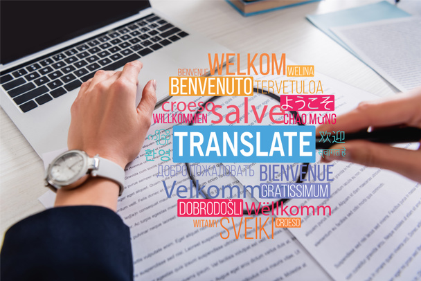 partial view of interpreter holding magnifier near documents, translate lettering near words in different languages illustration. Translation: "welcome" - Foto, Imagen