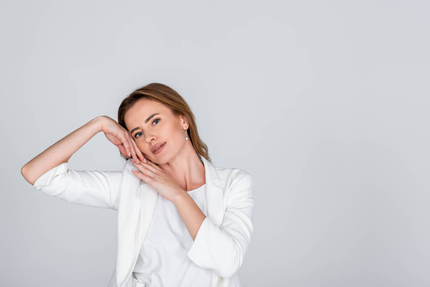 woman in white outfit looking at camera while posing isolated on grey - Fotografie, Obrázek