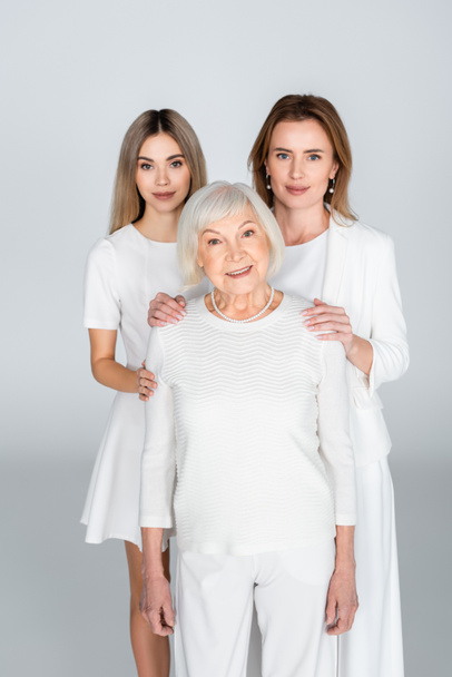 mother and daughter near smiling grandma on grey, generation of women  - Photo, image