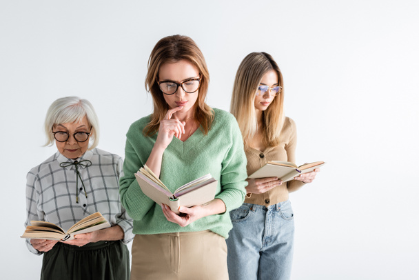 drie generaties intelligente vrouwen in glazen leesboeken geïsoleerd op wit - Foto, afbeelding