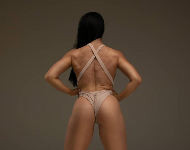 Fitness young woman standing on dark background, back view  - Φωτογραφία, εικόνα