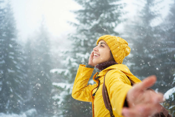 inspired traveler girl enjoying snowy winter walk in forest, feeling good concept, follow me hand - Foto, imagen
