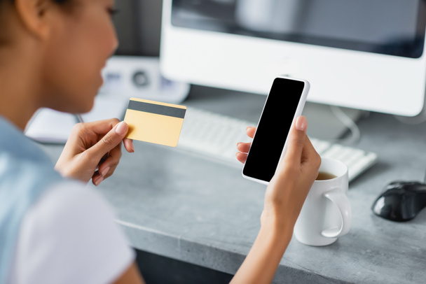 vista recortada de mujer afroamericana sosteniendo teléfono inteligente con pantalla en blanco y tarjeta de crédito - Foto, Imagen
