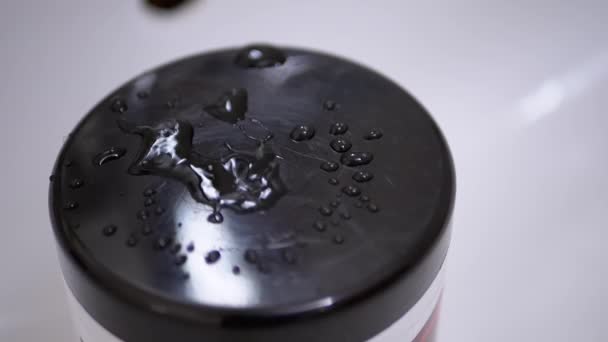 Druppels water vallen langzaam uit de kraan en spuiten op zwarte oppervlakte van plastic Cover - Video