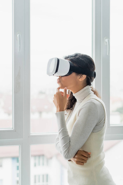 thoughtful african american woman in vr headset looking through window at home - Fotografie, Obrázek