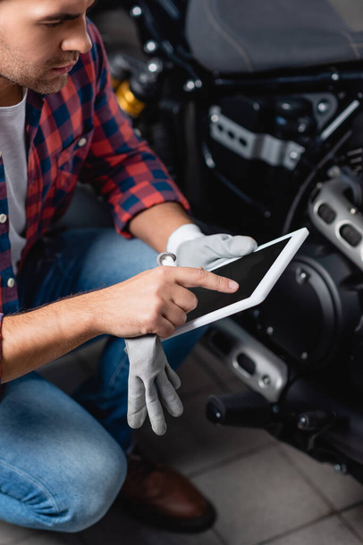 mladý mechanik ukazující prstem na digitální tablet v dílně - Fotografie, Obrázek