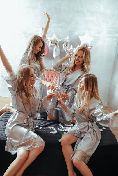 Belle giovani donne che bevono vino in pigiama party a casa - Foto, immagini