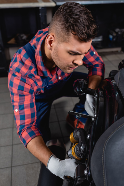 technicien en chemise à carreaux examinant amortisseur de moto en atelier - Photo, image