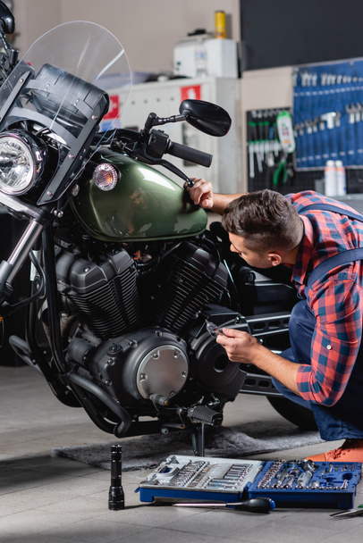 mechanic making diagnostics of motorcycle in workshop near toolbox - Photo, Image