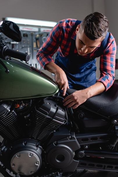 mladý mechanik ukazuje prstem při diagnostice motocyklu v dílně - Fotografie, Obrázek