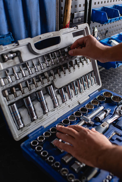 Ausgeschnittene Ansicht des Mechanikers bei der Auswahl des Instruments im Werkzeugkasten, verschwommener Vordergrund - Foto, Bild