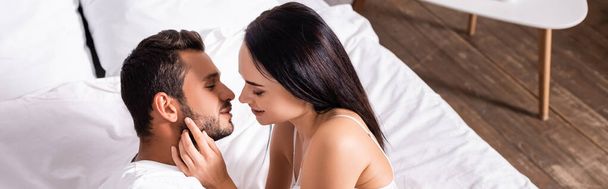 high angle view of sexy woman seducing young man in bedroom, banner - Photo, Image