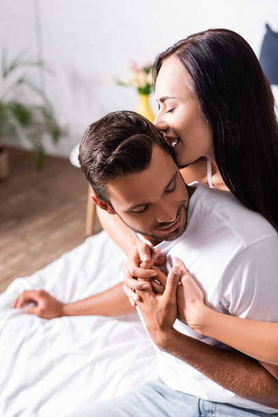 seductive brunette woman biting man in bedroom on blurred background - Zdjęcie, obraz