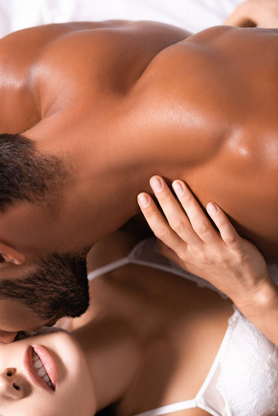 vue recadrée de musclé torse nu homme embrasser femme en lingerie à l'intérieur - Photo, image