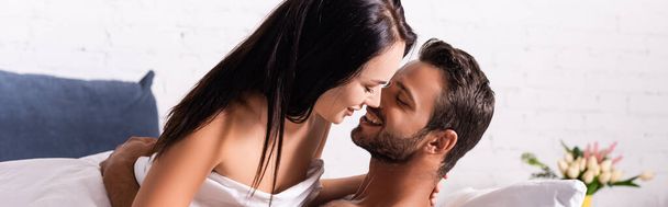 šťastný mladý muž objímání brunetka žena v ložnici na rozmazaném pozadí, banner - Fotografie, Obrázek