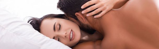 widok z tyłu młody mężczyzna całuje zmysłowy kobieta z zamkniętymi oczami na łóżku, baner - Zdjęcie, obraz