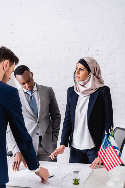 seria mujer de negocios árabe señalando con el dedo cerca de plano durante la reunión con socios comerciales interracial - Foto, imagen