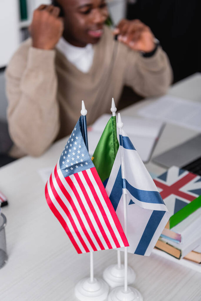 selective focus of american and israeli flags near dictionaries and african american translator on blurred background - Foto, imagen