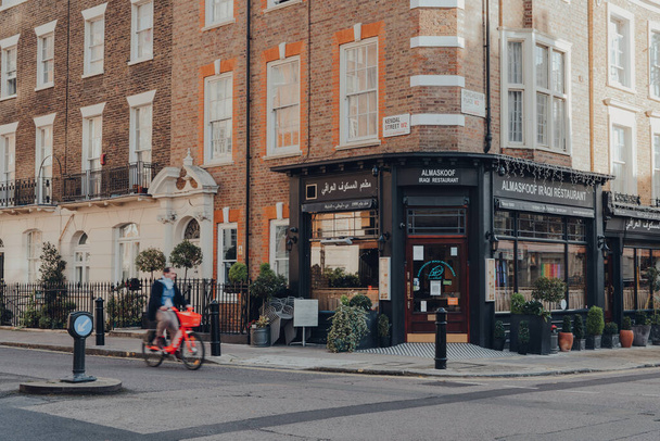 London, UK - December 5,2020: Front of closed Almaskoof Iraqi restaurant in Mayfair, affluent area in the West End of London in the City of Westminster borough, man on a bike riding past, motion blur. - Foto, imagen