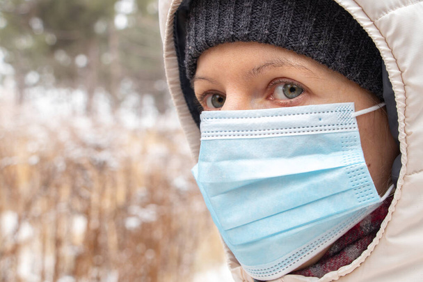 девушка лицом к лицу медицинская маска зимой на открытом воздухе крупным планом - Фото, изображение