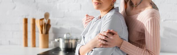 cropped view of lesbian woman embracing girlfriend in kitchen, banner - Foto, afbeelding