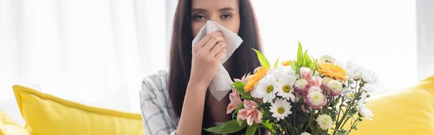 mujer alérgica limpiando la nariz con servilleta de papel cerca de flores, pancarta - Foto, imagen
