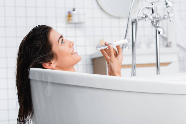 cheerful woman talking on mobile phone while taking bath - Photo, image