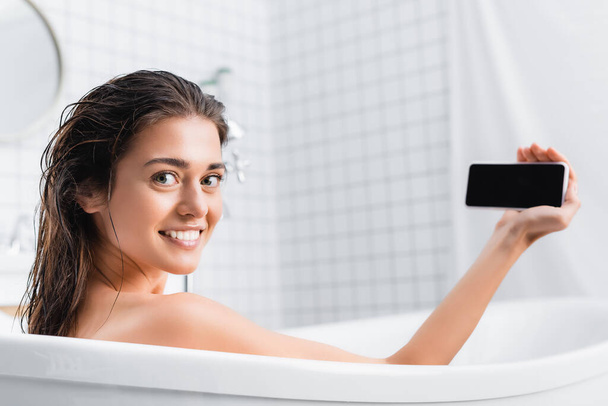 felice giovane donna prendendo selfie mentre si fa il bagno e sorridendo alla fotocamera - Foto, immagini