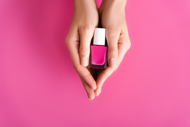 cropped view of woman holding vial of nail polish on pink background - Fotografie, Obrázek