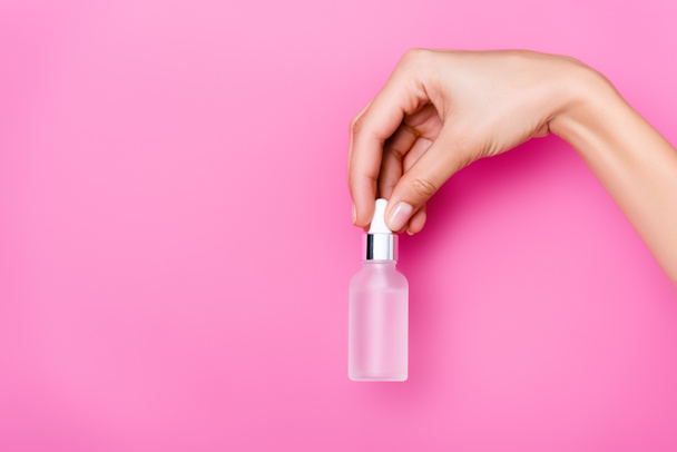 partial view of woman with bottle of cuticle remover on pink background - Foto, imagen
