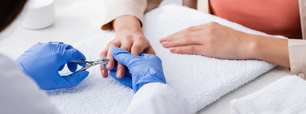 selective focus of cuticle nipper in hands of manicurist making manicure to client, cropped view, banner - Photo, Image