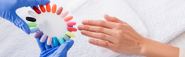 vue partielle de manucure tenant ensemble de faux ongles multicolores près de la main du client, bannière - Photo, image
